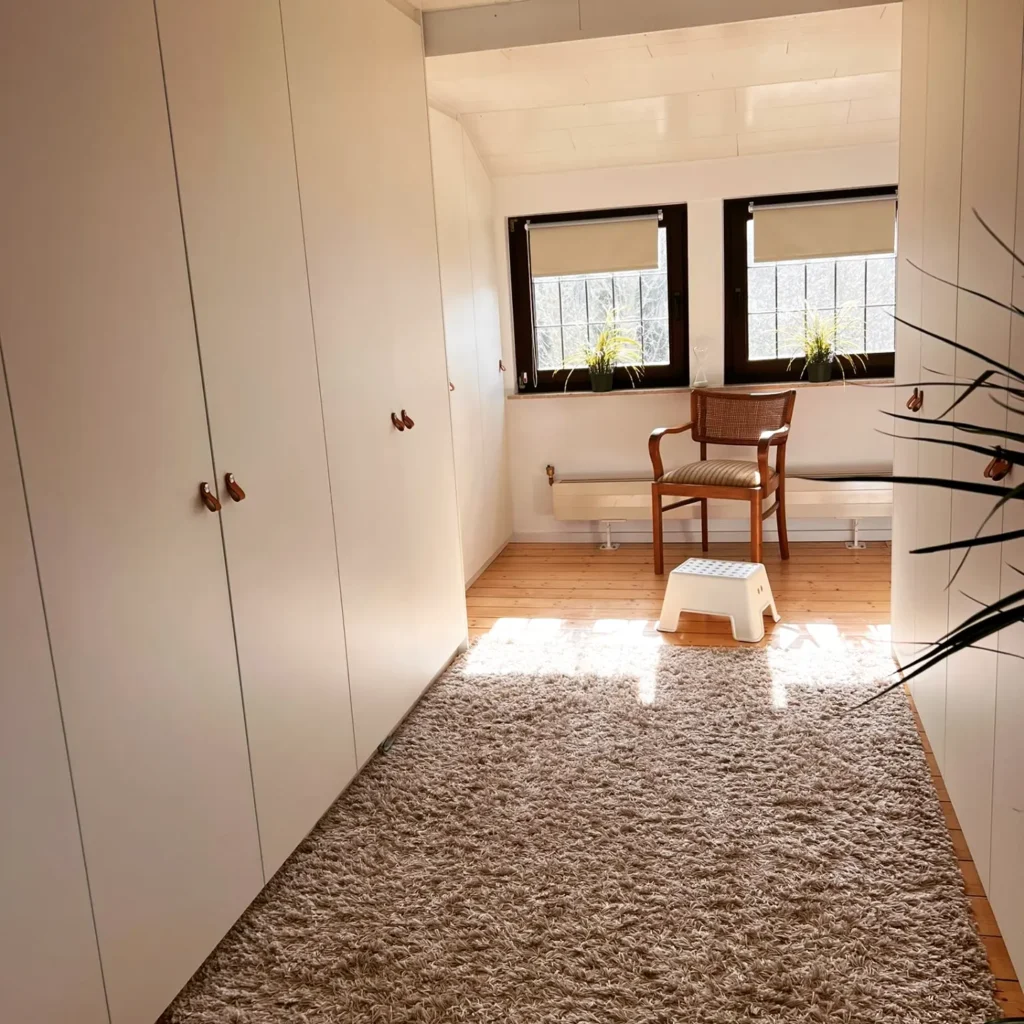 Ein Zimmer mit Parketbode und weißen Schrankwänden