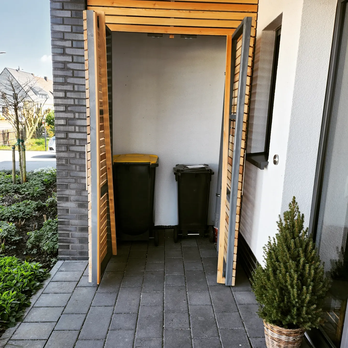Mülltonnenverkleidung aus Holz mit geöffneten Türen
